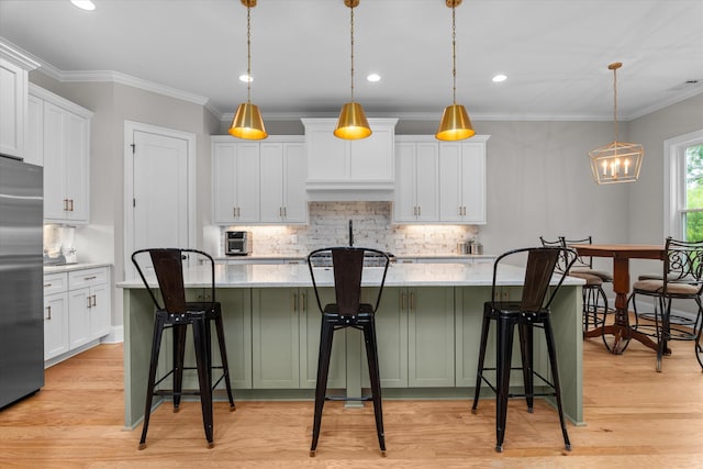 552 River Oaks Ln, Evans, GA 30809 - kitchen with built in fridge, tasteful backsplash, white cabinets, a center island with sink, and crown molding