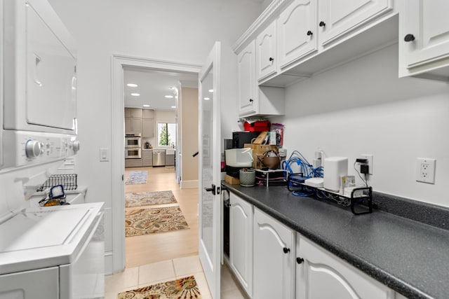 29 Savannah River Pl, North Augusta, SC 29841 - interior space featuring dark countertops, appliances with stainless steel finishes, stacked washer / drying machine, white cabinetry, and light tile patterned flooring