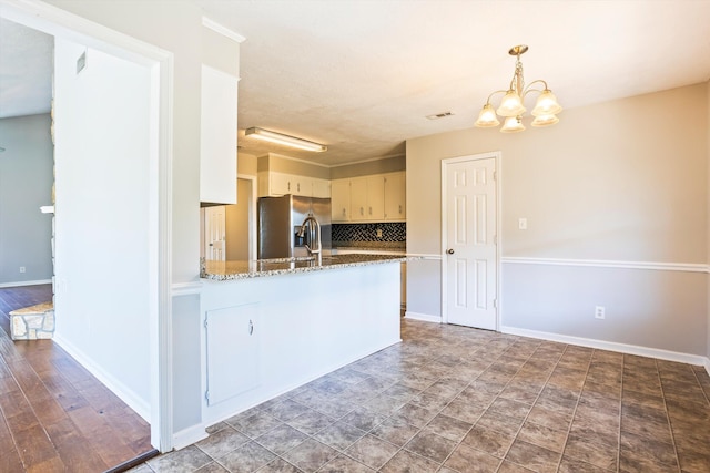 661 Kemper Dr, Evans, GA 30809 - kitchen featuring stainless steel refrigerator with ice dispenser, a chandelier, decorative backsplash, a peninsula, and stone counters