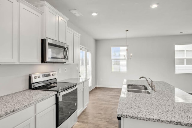 kitchen with white cabinets, appliances with stainless steel finishes, hanging light fixtures, and sink