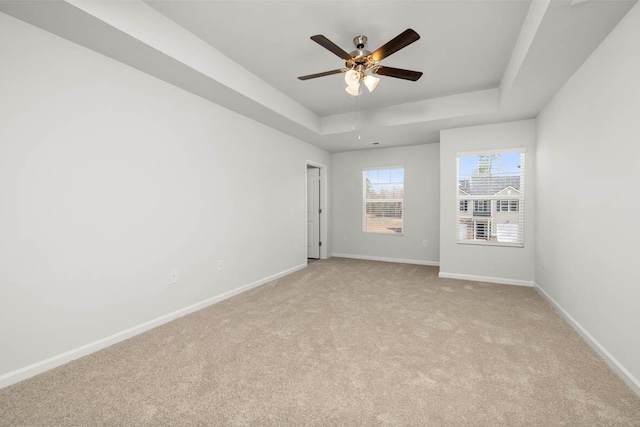 carpeted spare room featuring a raised ceiling and ceiling fan