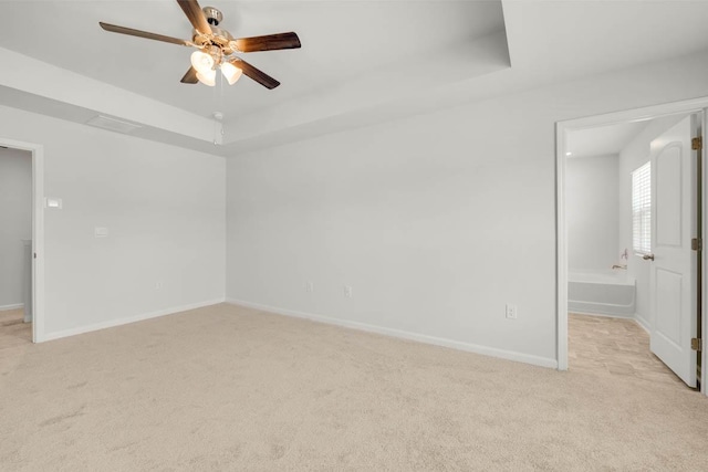 carpeted spare room featuring a raised ceiling and ceiling fan