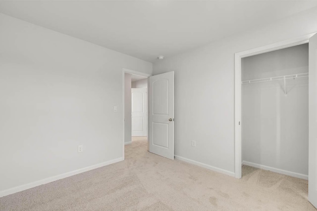 unfurnished bedroom featuring light carpet and a closet