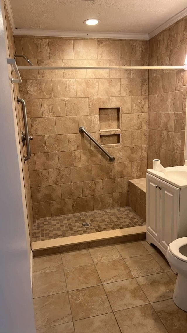 bathroom with a textured ceiling, tiled shower, toilet, and crown molding