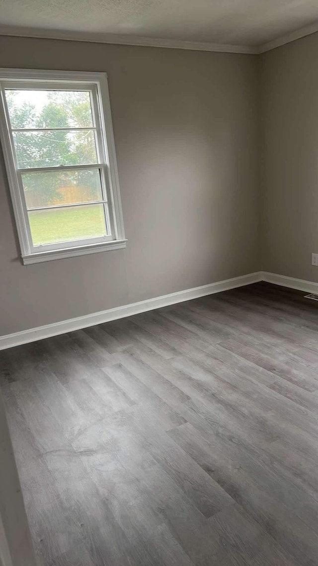 empty room with hardwood / wood-style floors and crown molding