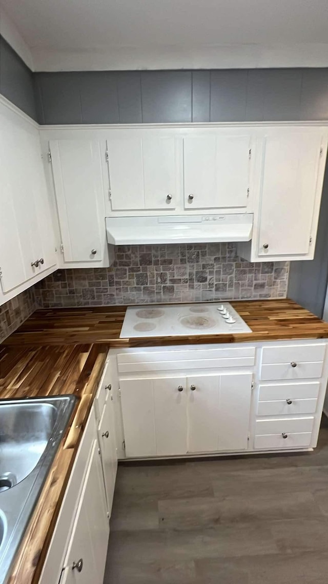 kitchen with backsplash, butcher block counters, white cabinets, and white stovetop