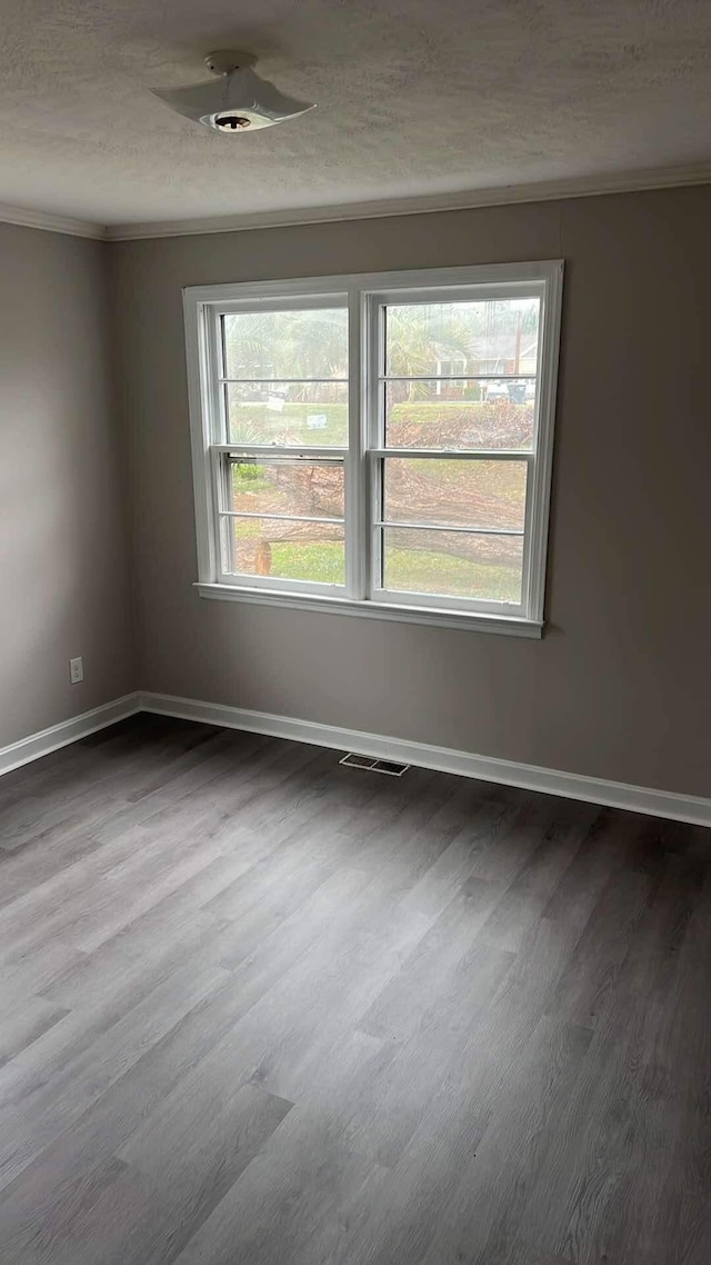 spare room with crown molding, hardwood / wood-style floors, and a textured ceiling