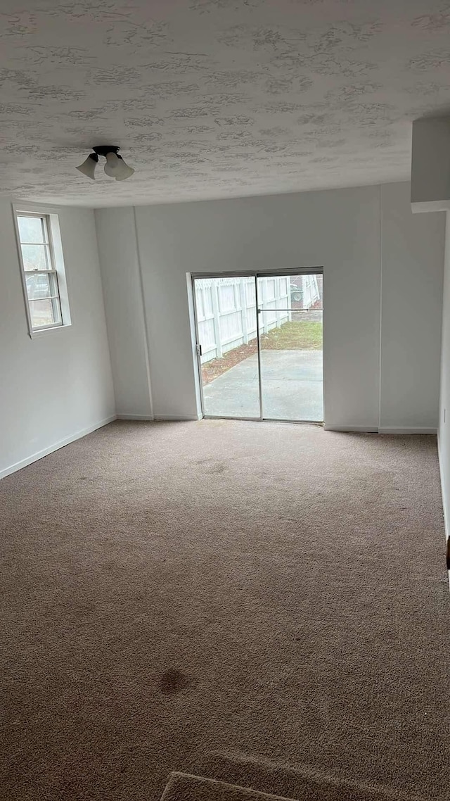 carpeted empty room featuring a textured ceiling