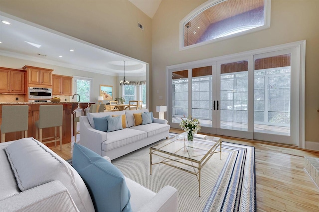 living room featuring light wood-type flooring, crown molding, and an inviting chandelier