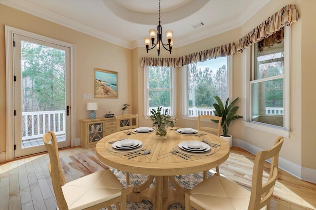 dining area with light wood-type flooring, crown molding, and a notable chandelier