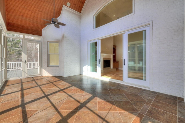 unfurnished sunroom featuring ceiling fan, wooden ceiling, and vaulted ceiling