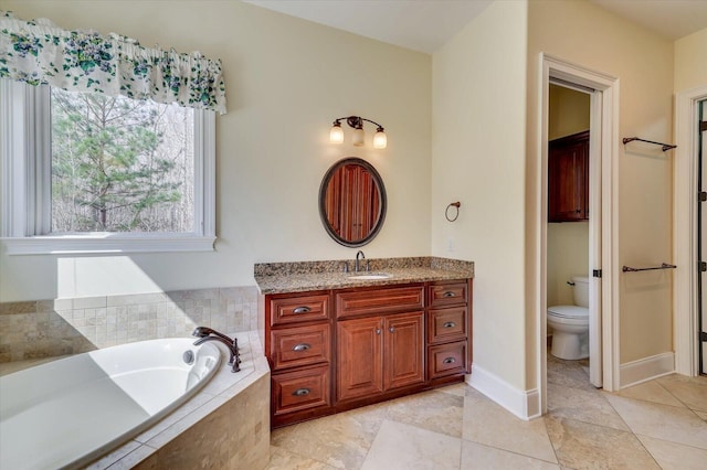 bathroom with tiled tub, vanity, and toilet