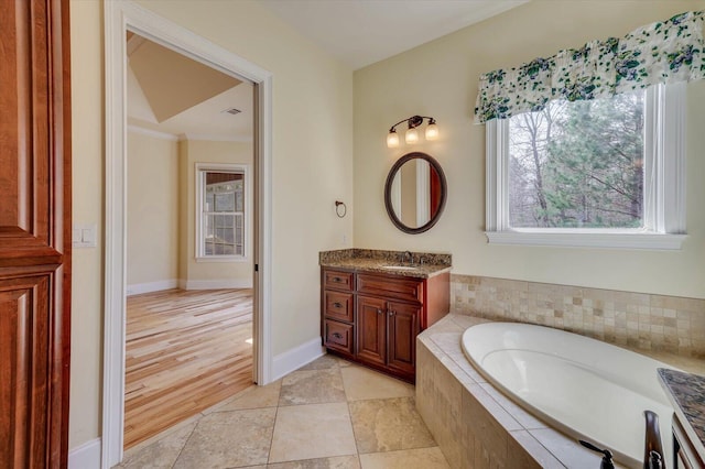 bathroom featuring tiled bath, vanity, and ornamental molding