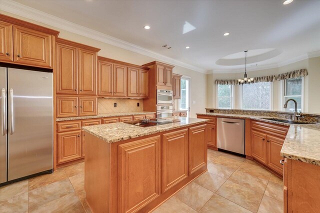 kitchen with stainless steel appliances, light stone counters, a notable chandelier, decorative light fixtures, and a kitchen island