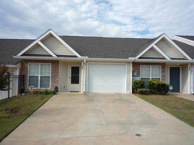 ranch-style house featuring driveway, brick siding, an attached garage, and fence