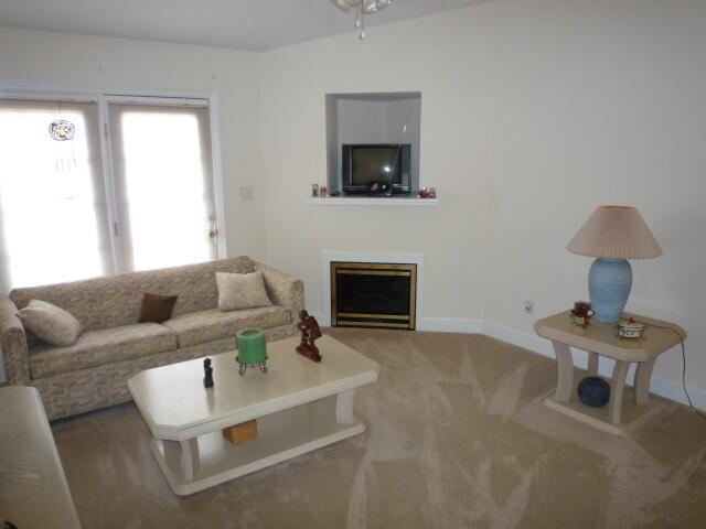 carpeted living room with a fireplace and baseboards