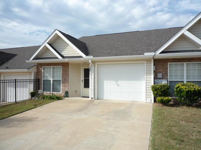 ranch-style house featuring concrete driveway, roof with shingles, an attached garage, and fence