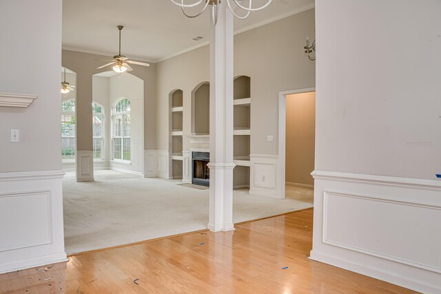 215 Mineral Ct, Evans, GA 30809 - unfurnished living room featuring built in shelves, crown molding, a ceiling fan, a fireplace, and a wainscoted wall