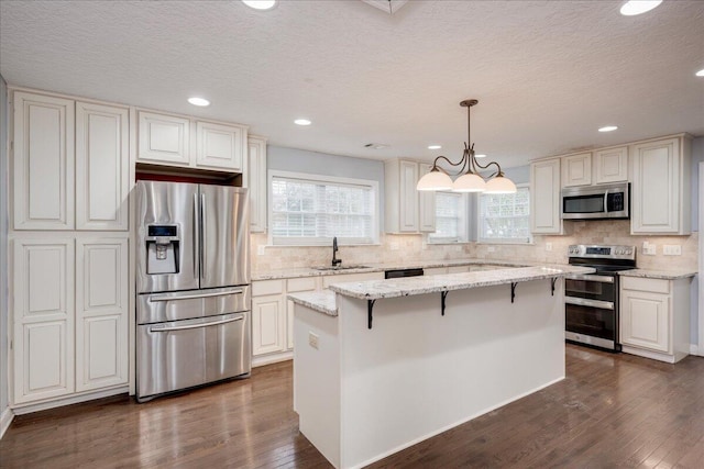 kitchen featuring pendant lighting, a kitchen island, sink, and stainless steel appliances