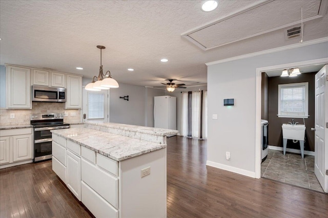 kitchen featuring a center island, stainless steel appliances, tasteful backsplash, a textured ceiling, and decorative light fixtures