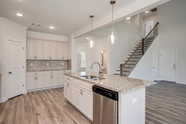 kitchen with backsplash, stainless steel dishwasher, sink, decorative light fixtures, and a center island with sink