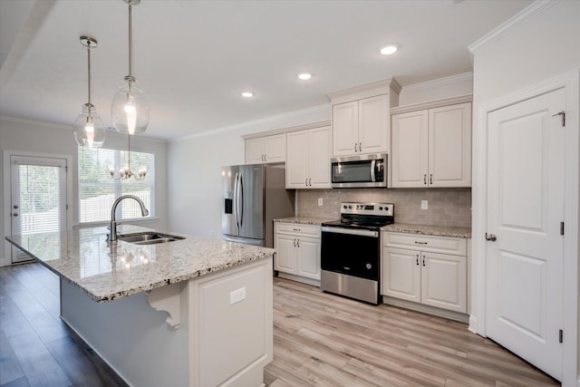 kitchen featuring stainless steel appliances, a kitchen island with sink, sink, white cabinetry, and hanging light fixtures