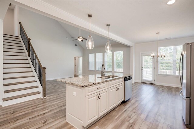 kitchen featuring appliances with stainless steel finishes, ceiling fan with notable chandelier, sink, white cabinets, and an island with sink