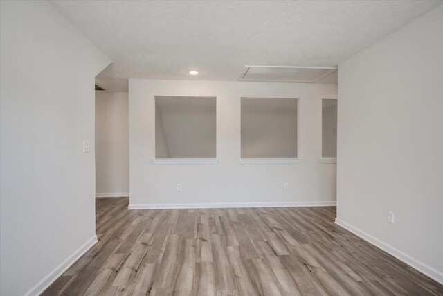 empty room with light hardwood / wood-style floors and a textured ceiling