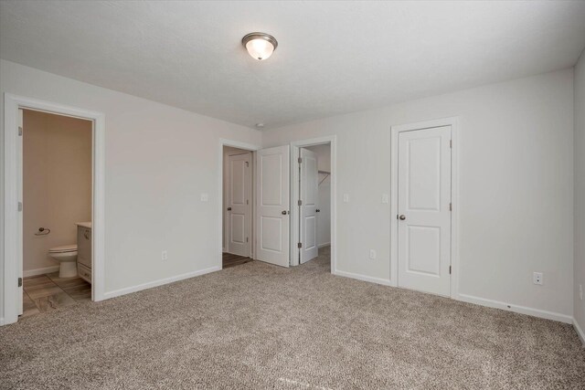 unfurnished bedroom featuring light colored carpet, connected bathroom, and a closet