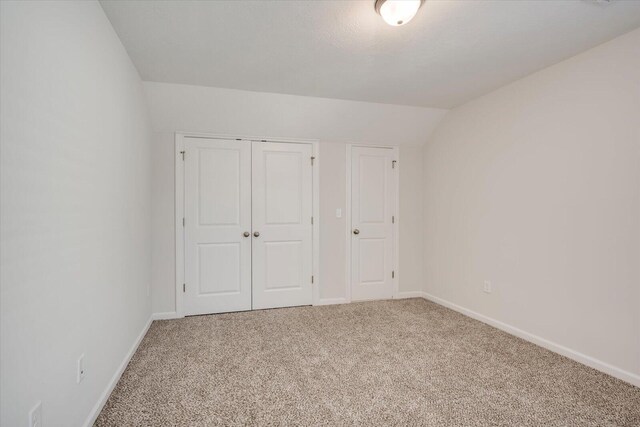 unfurnished bedroom featuring a closet, carpet floors, and lofted ceiling