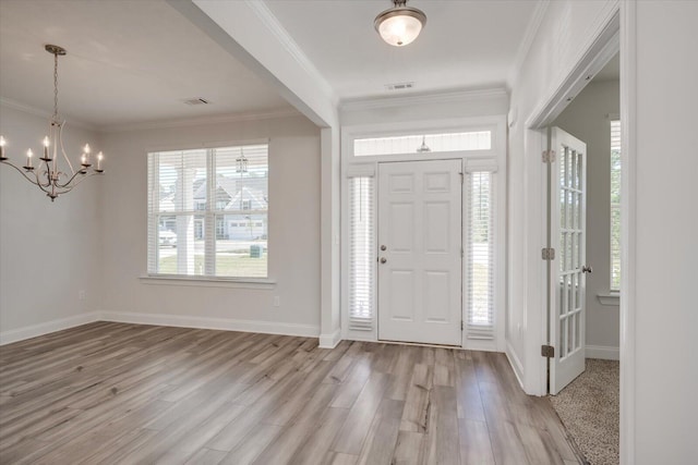 entryway featuring light hardwood / wood-style flooring, ornamental molding, and a notable chandelier