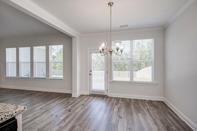 unfurnished dining area featuring hardwood / wood-style floors, crown molding, and an inviting chandelier