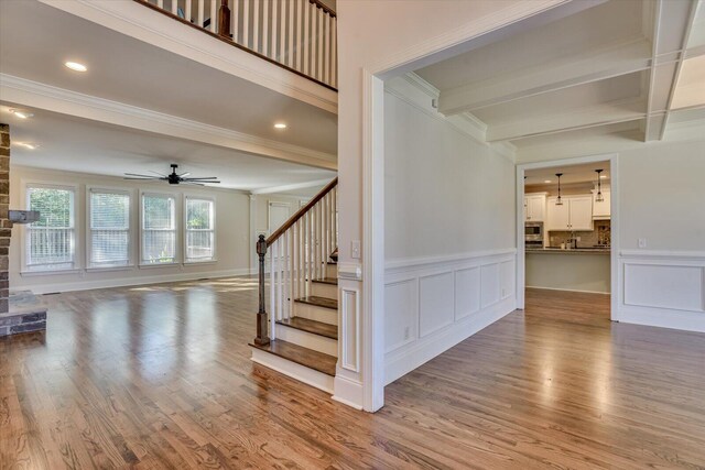 staircase featuring hardwood / wood-style flooring, ceiling fan, beam ceiling, and crown molding