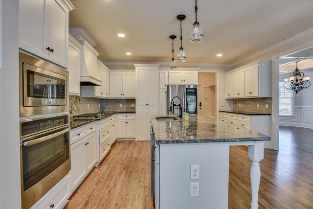 kitchen with white cabinets, decorative light fixtures, and stainless steel appliances