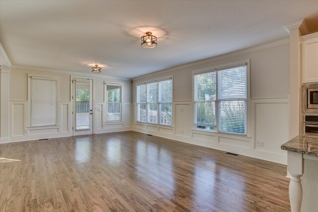 unfurnished living room featuring hardwood / wood-style floors and ornamental molding