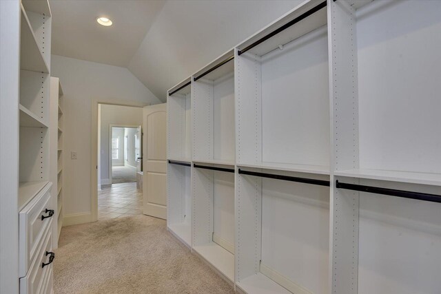 spacious closet with light colored carpet and vaulted ceiling