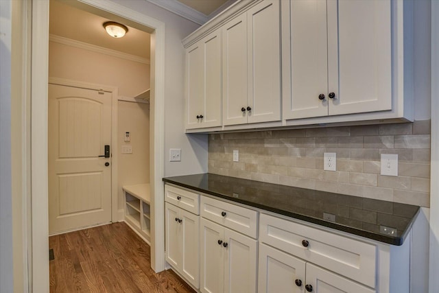 kitchen with white cabinets, decorative backsplash, crown molding, and hardwood / wood-style flooring