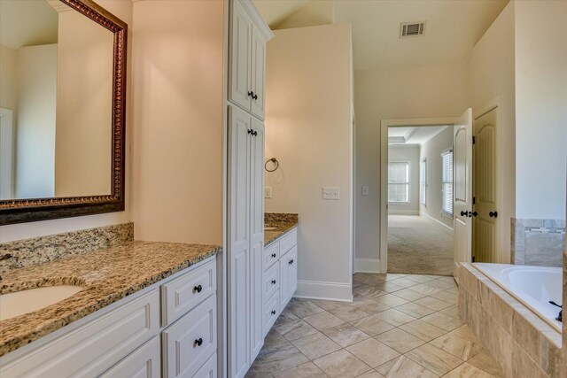 bathroom featuring tiled tub and vanity