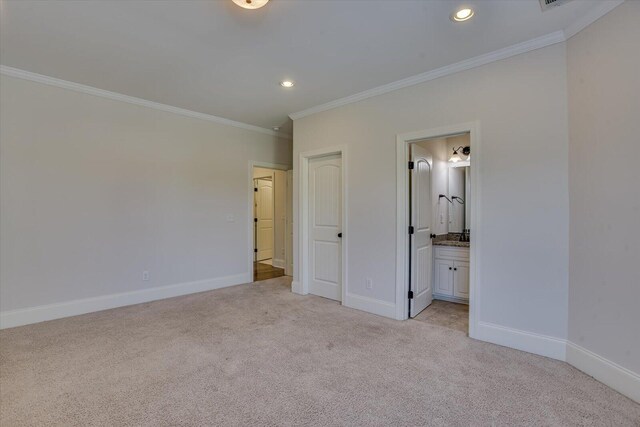 unfurnished bedroom featuring ornamental molding, light carpet, and ensuite bath