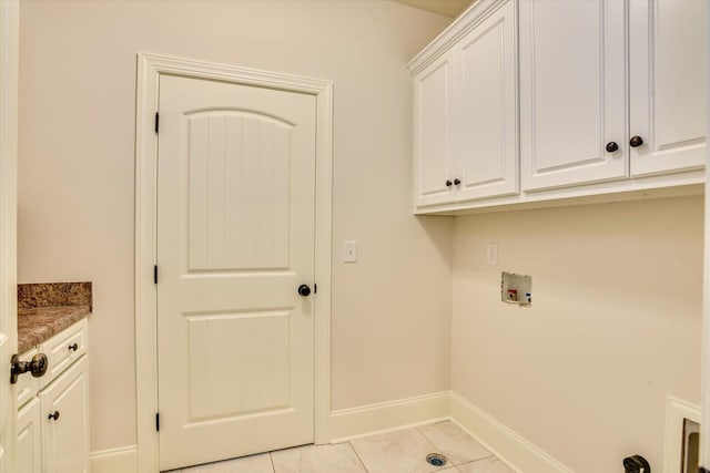 clothes washing area with cabinets, light tile patterned floors, and washer hookup