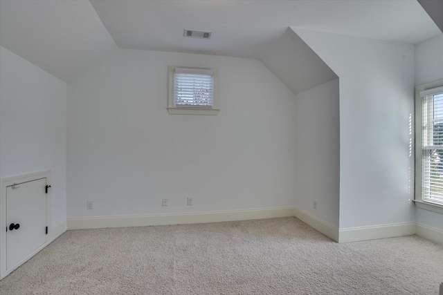 additional living space with a wealth of natural light, light colored carpet, and lofted ceiling