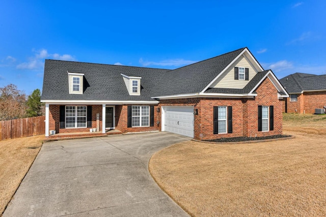 view of front of house featuring cooling unit, a garage, covered porch, and a front yard