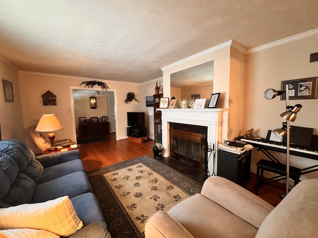 living room with a glass covered fireplace, wood finished floors, visible vents, and ornamental molding