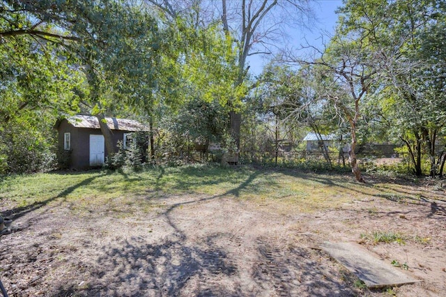 view of yard featuring a shed, fence, and an outbuilding