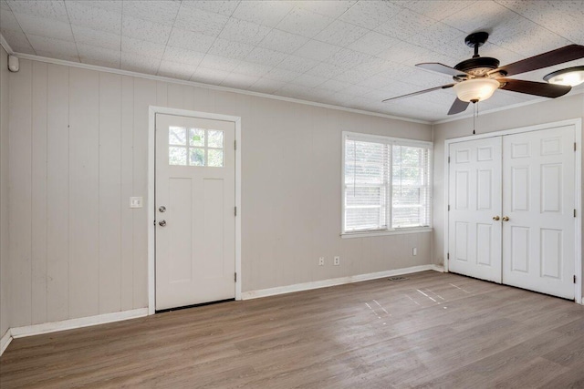 foyer featuring ornamental molding, a ceiling fan, baseboards, and wood finished floors