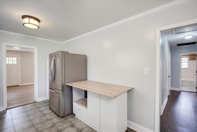 kitchen featuring light wood-style flooring, baseboards, light countertops, freestanding refrigerator, and crown molding