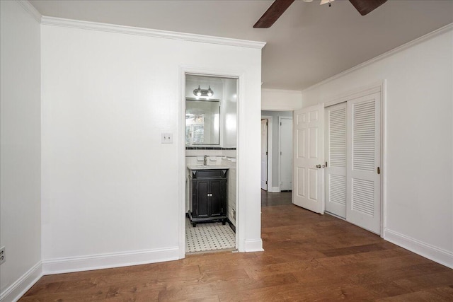 hall with ornamental molding, a sink, baseboards, and wood finished floors