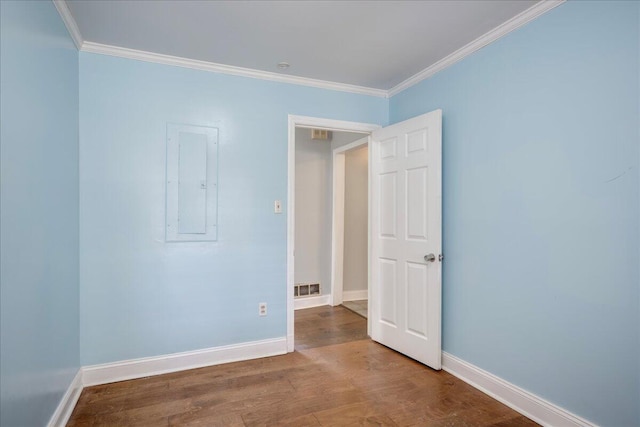 spare room with electric panel, visible vents, crown molding, and wood finished floors