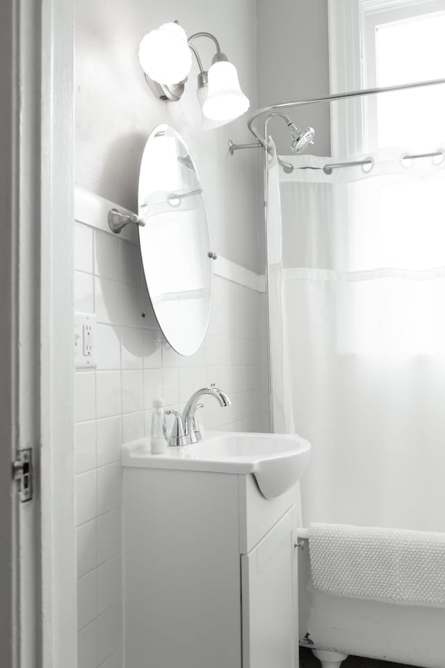 bathroom with vanity, curtained shower, and tile walls