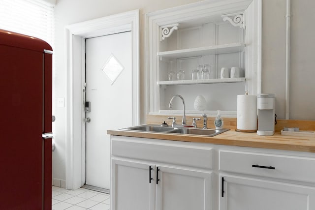 bar featuring butcher block countertops, sink, white cabinets, and light tile patterned flooring